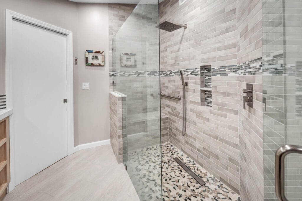 Modern bathroom with a walk-in shower featuring gray tiles and pebble floor.