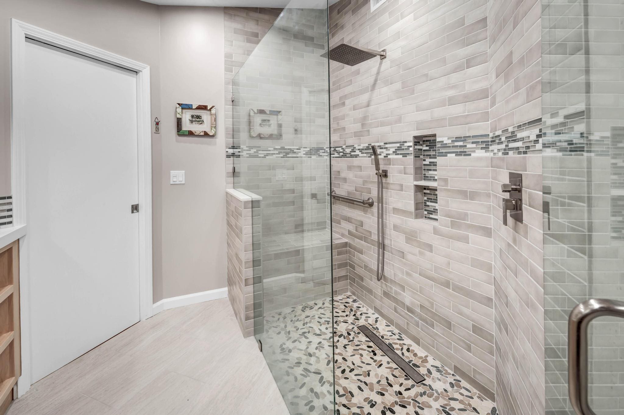 Modern bathroom with a walk-in shower featuring gray tiles and pebble floor.
