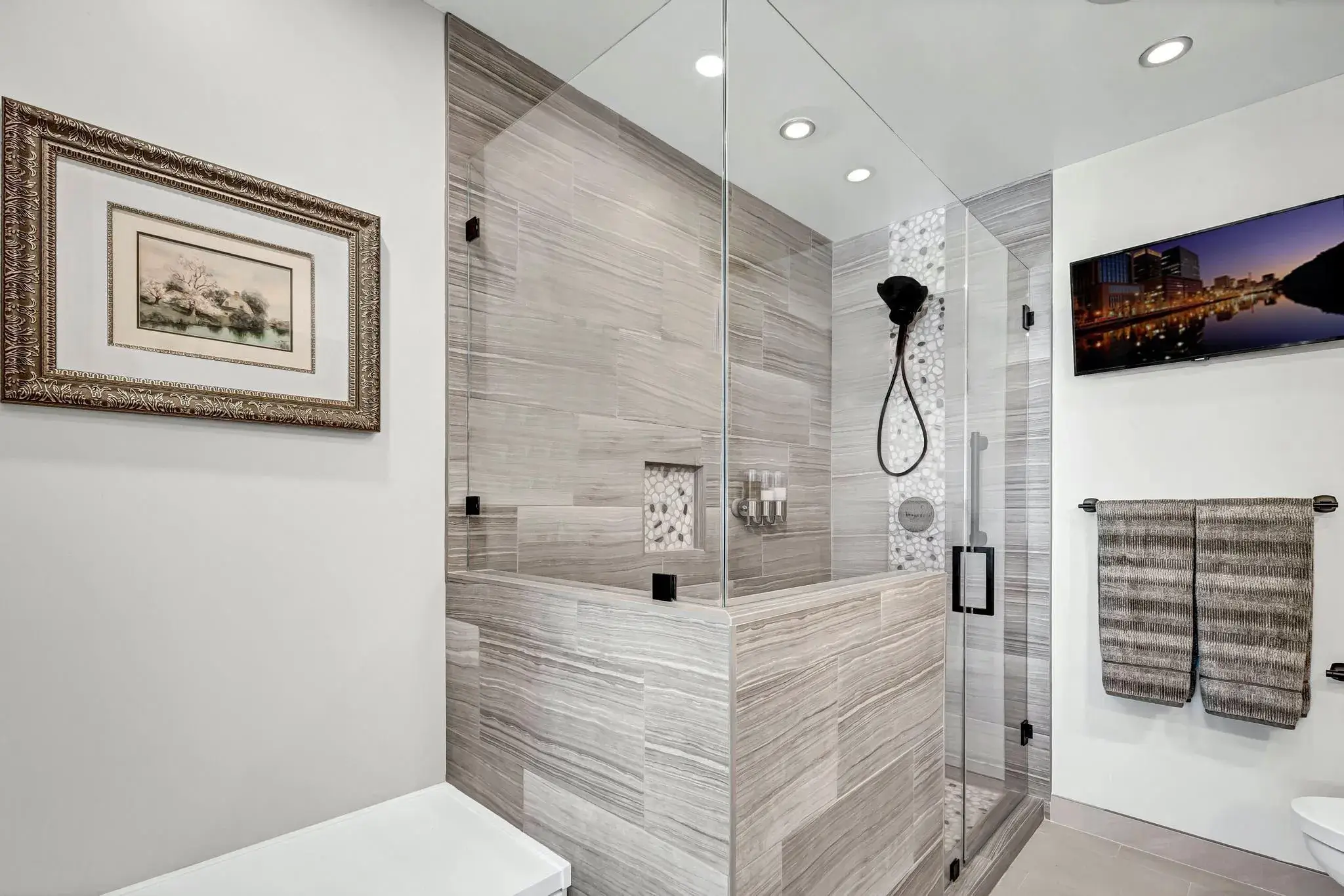 Modern bathroom with walk-in shower, tiled walls, and framed artwork