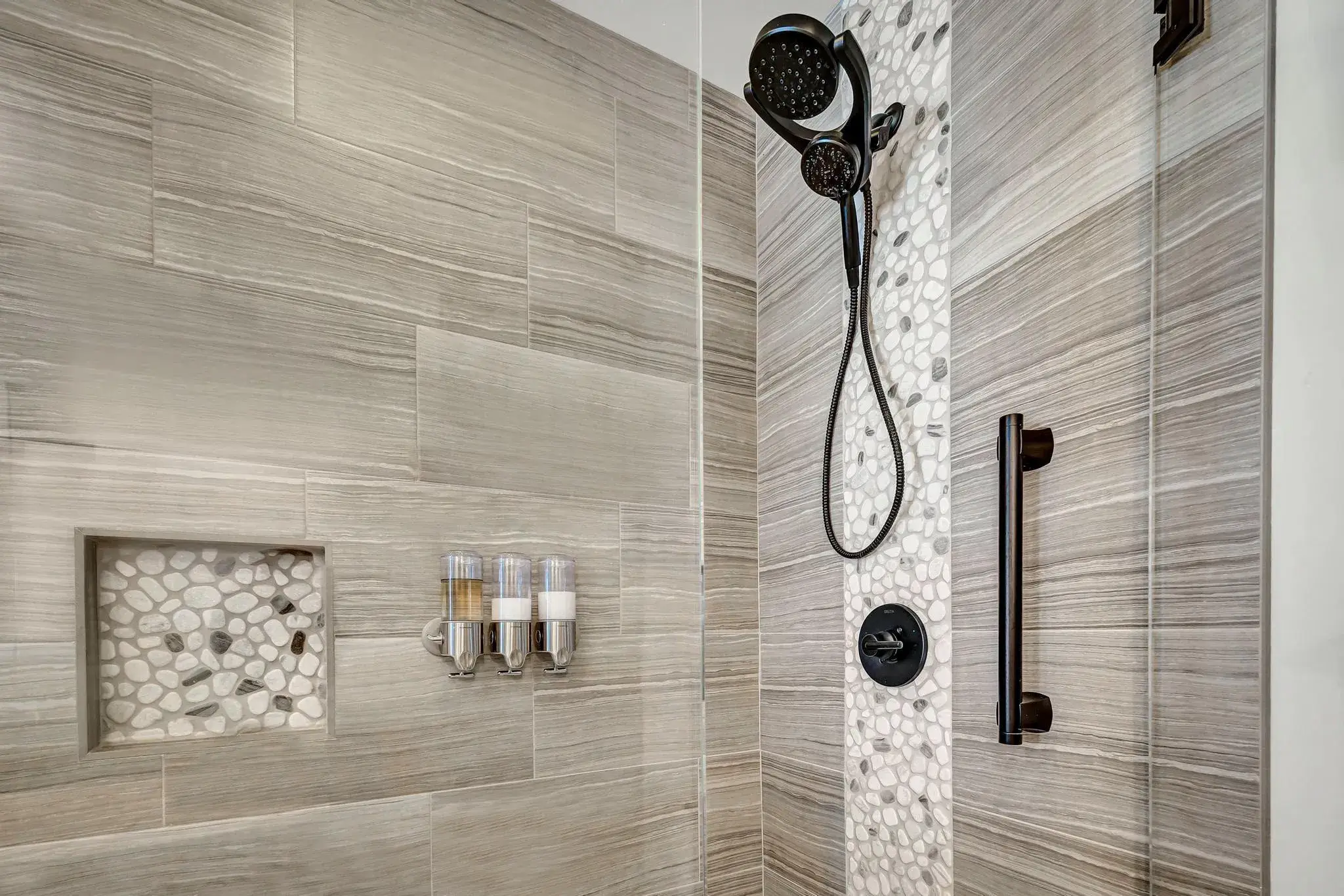Modern shower with gray wood-look tiles and pebble accents