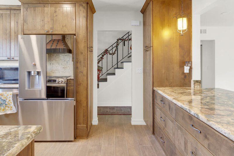 Modern kitchen with stainless steel refrigerator and wooden cabinets.