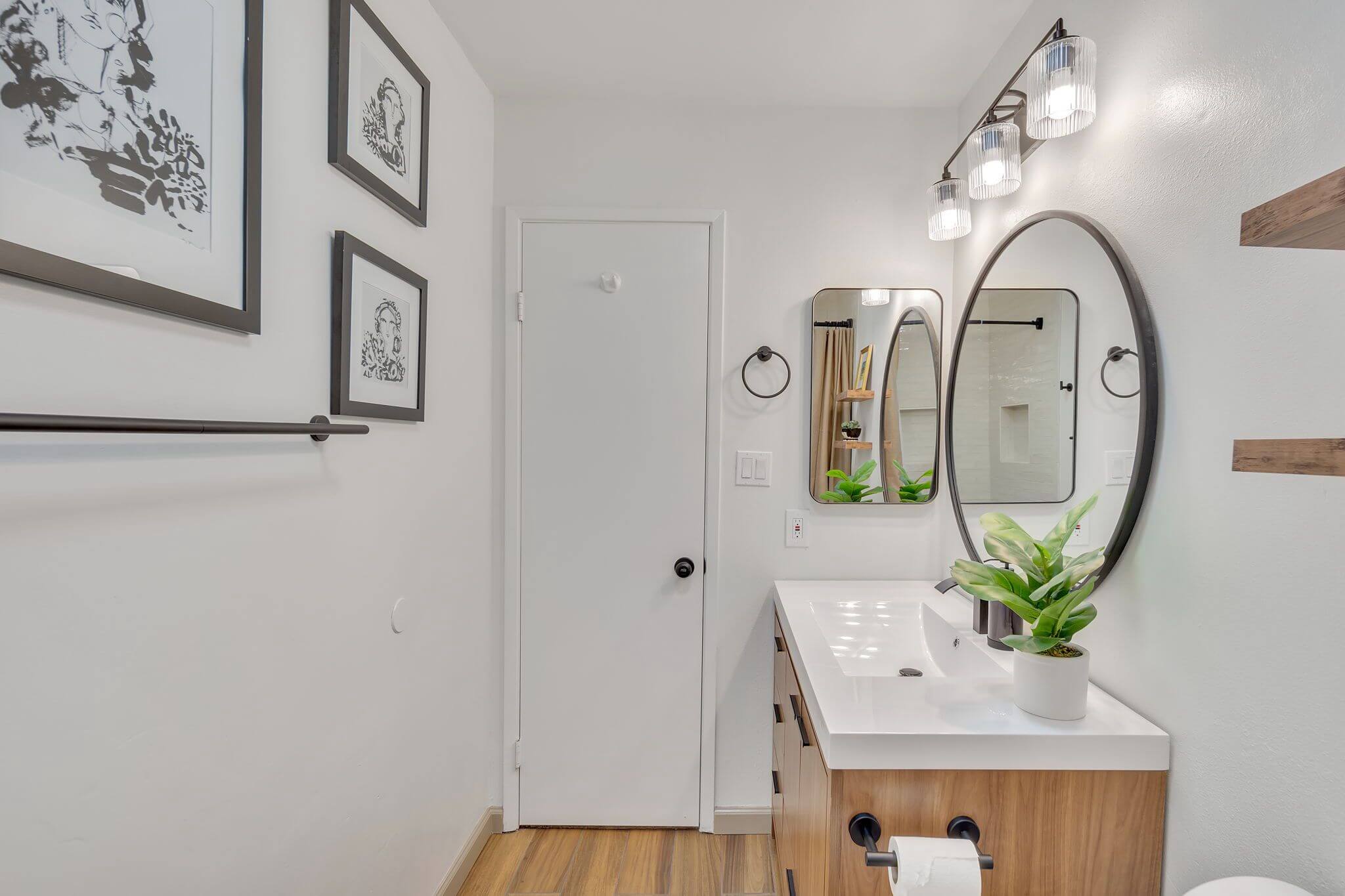 Modern bathroom with white walls, wood vanity, and two mirrors
