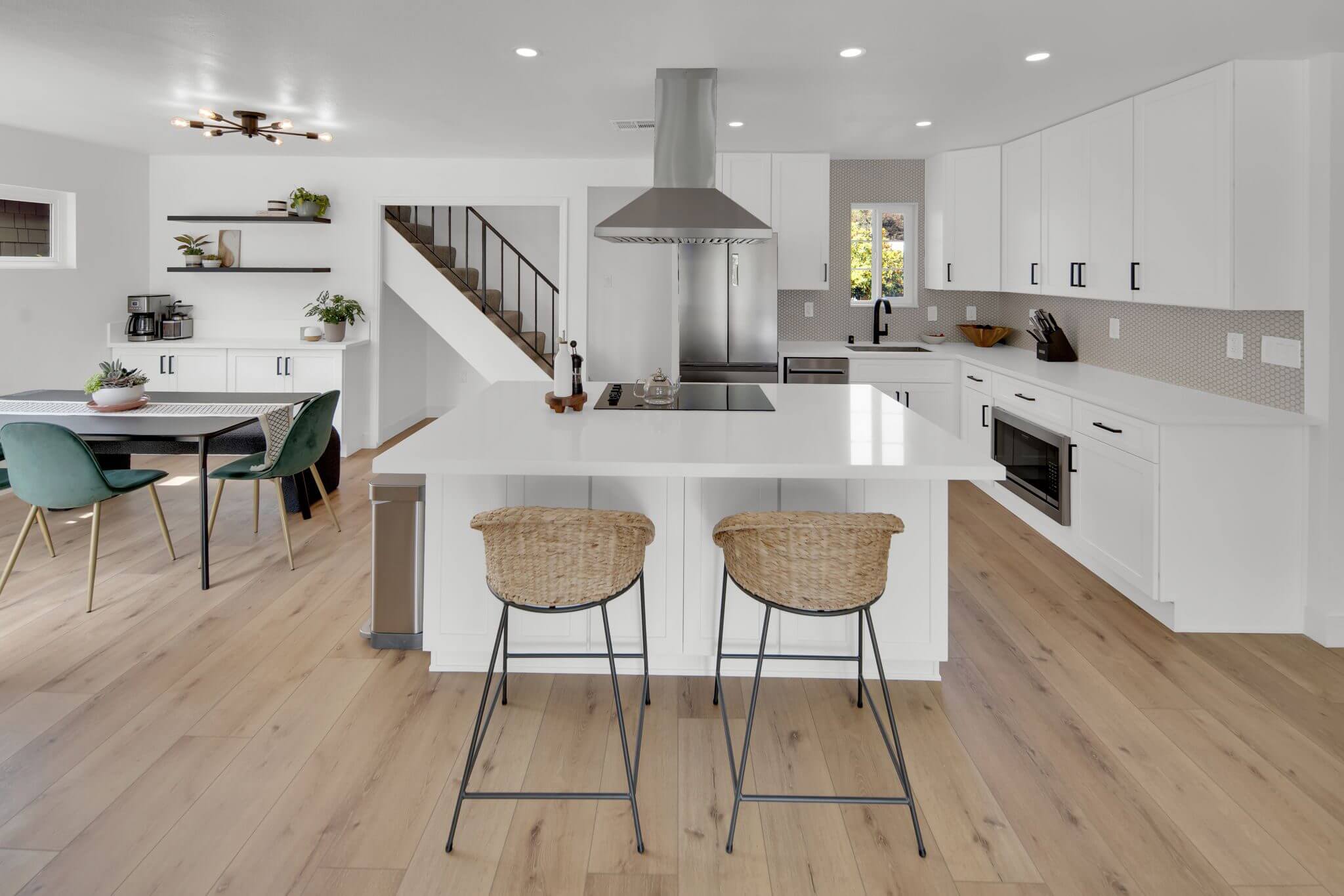 Modern kitchen with white cabinets, large island, and dining area.