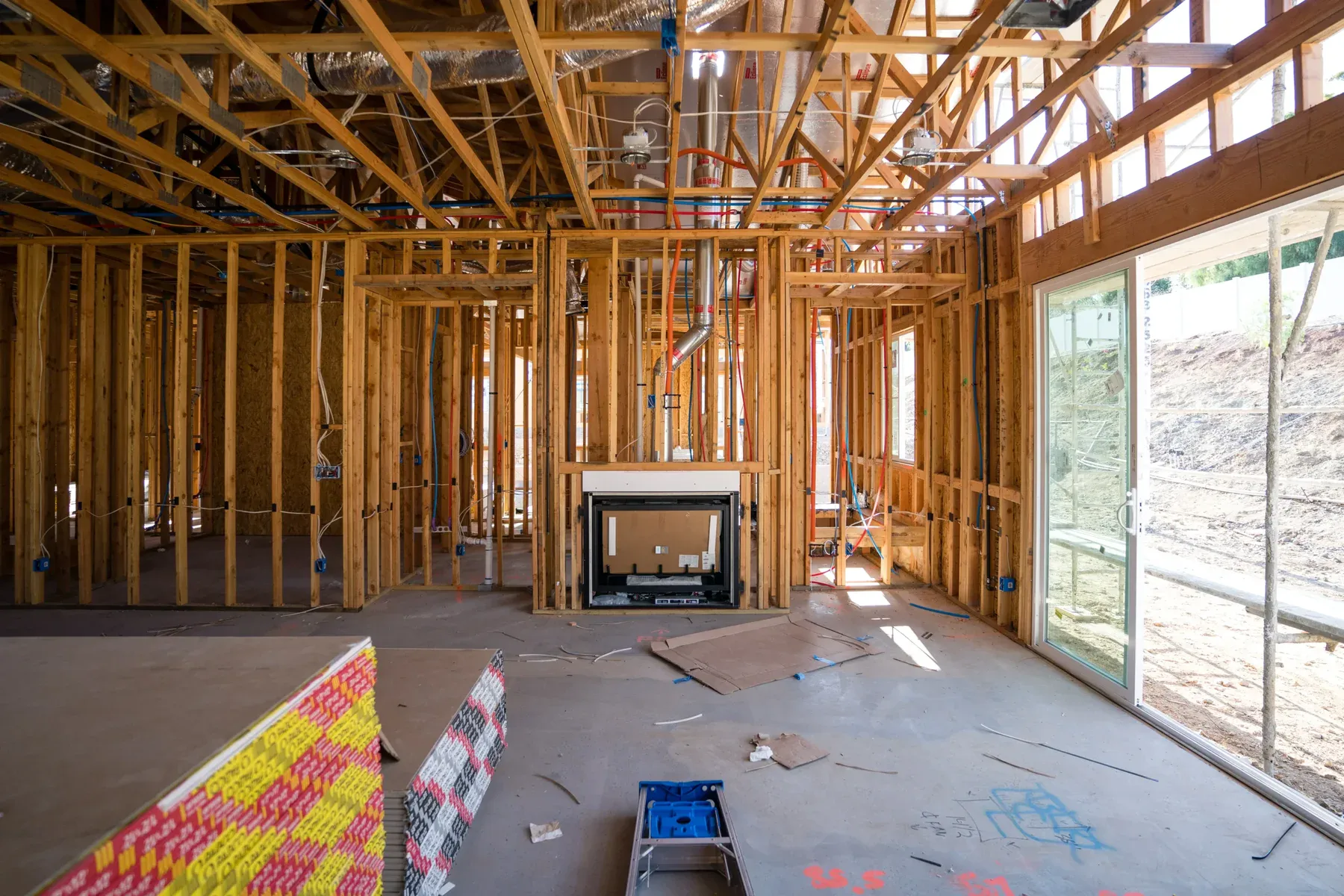 Interior of a house under construction with exposed wooden framing and a fireplace.