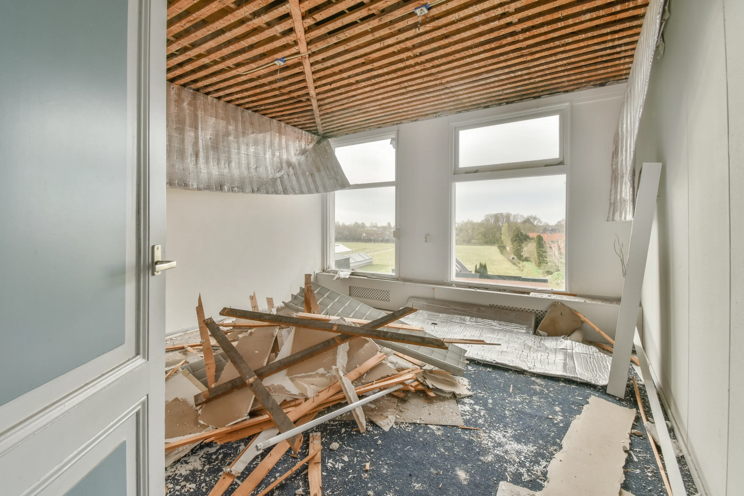 Room under renovation with exposed ceiling beams and construction debris on the floor