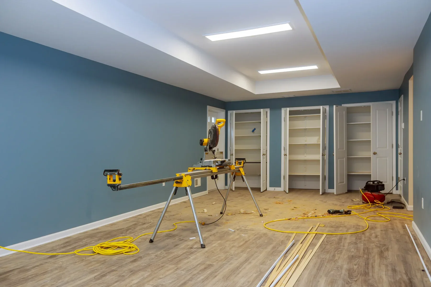 Miter saw on stand in a room with blue walls and wood flooring
