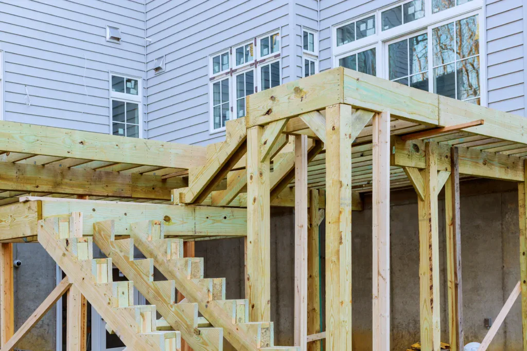 New wooden deck frame and stairs under construction next to a house