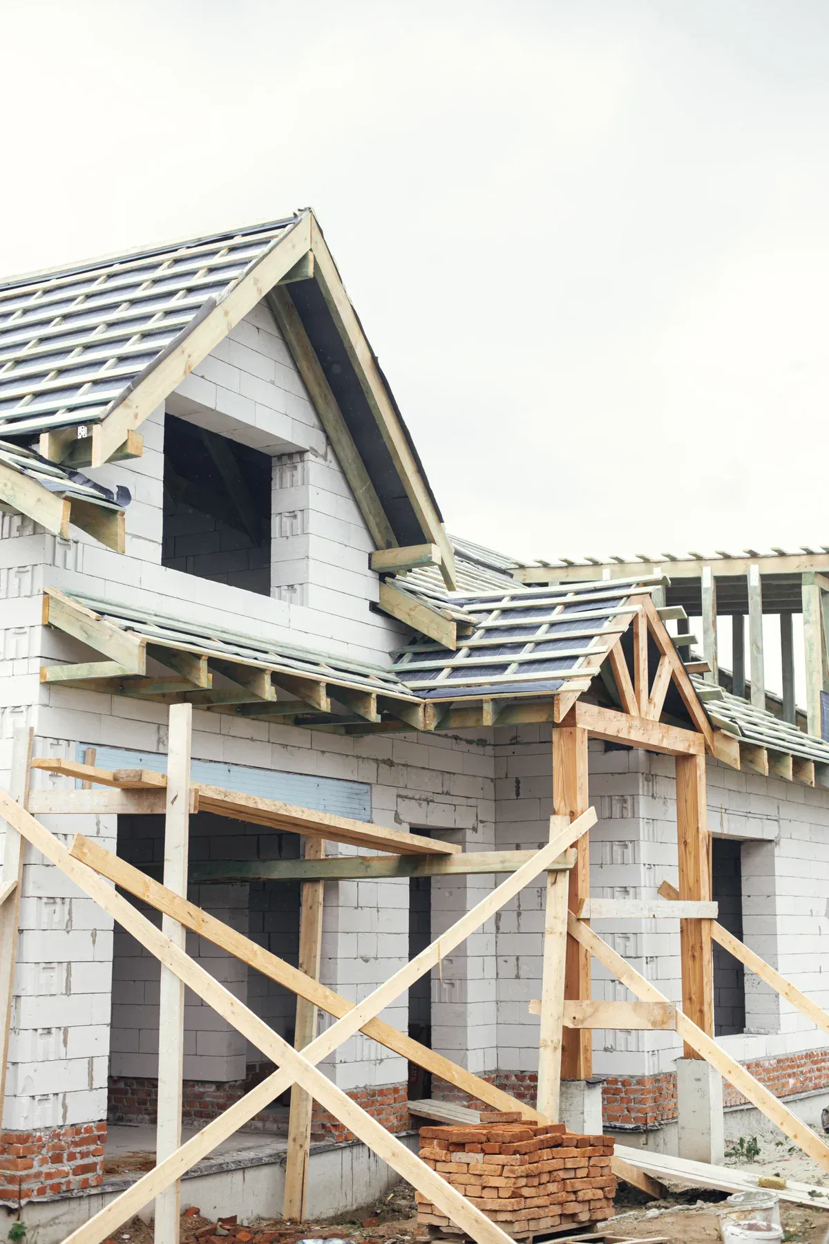 New house under construction with visible roof framing and brick foundation.