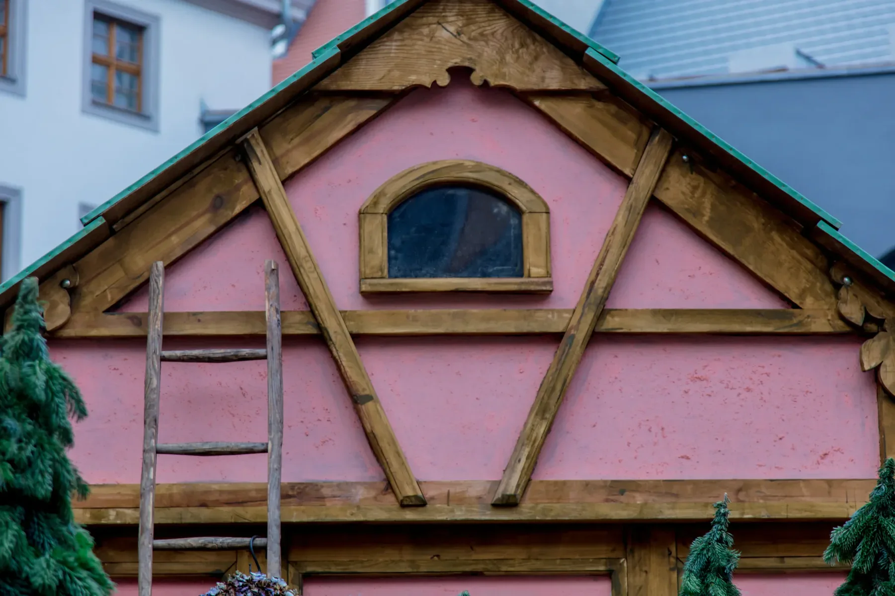 Pink house facade with wooden beams and an arched window