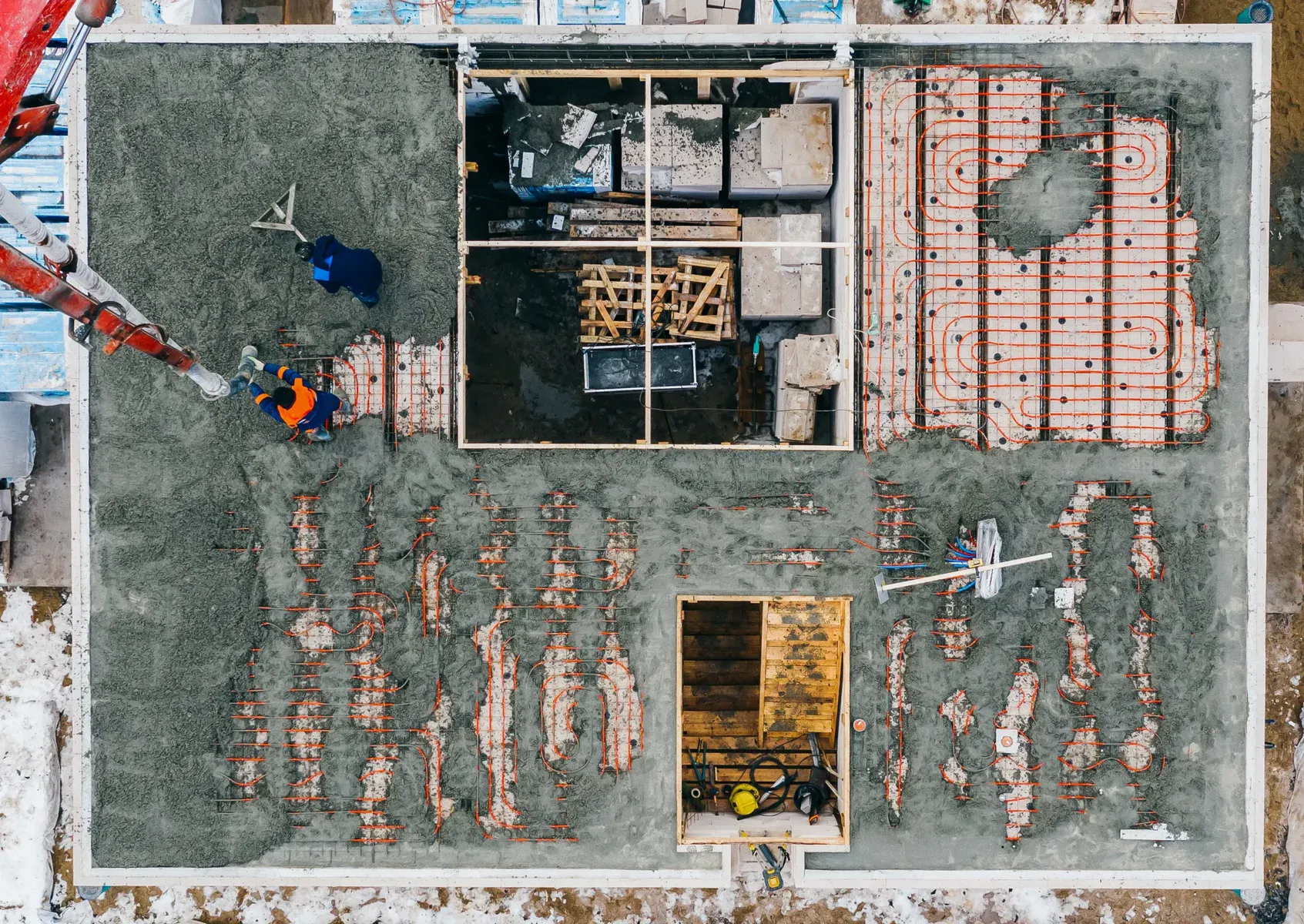 Aerial view of a construction site with workers and underfloor heating pipes