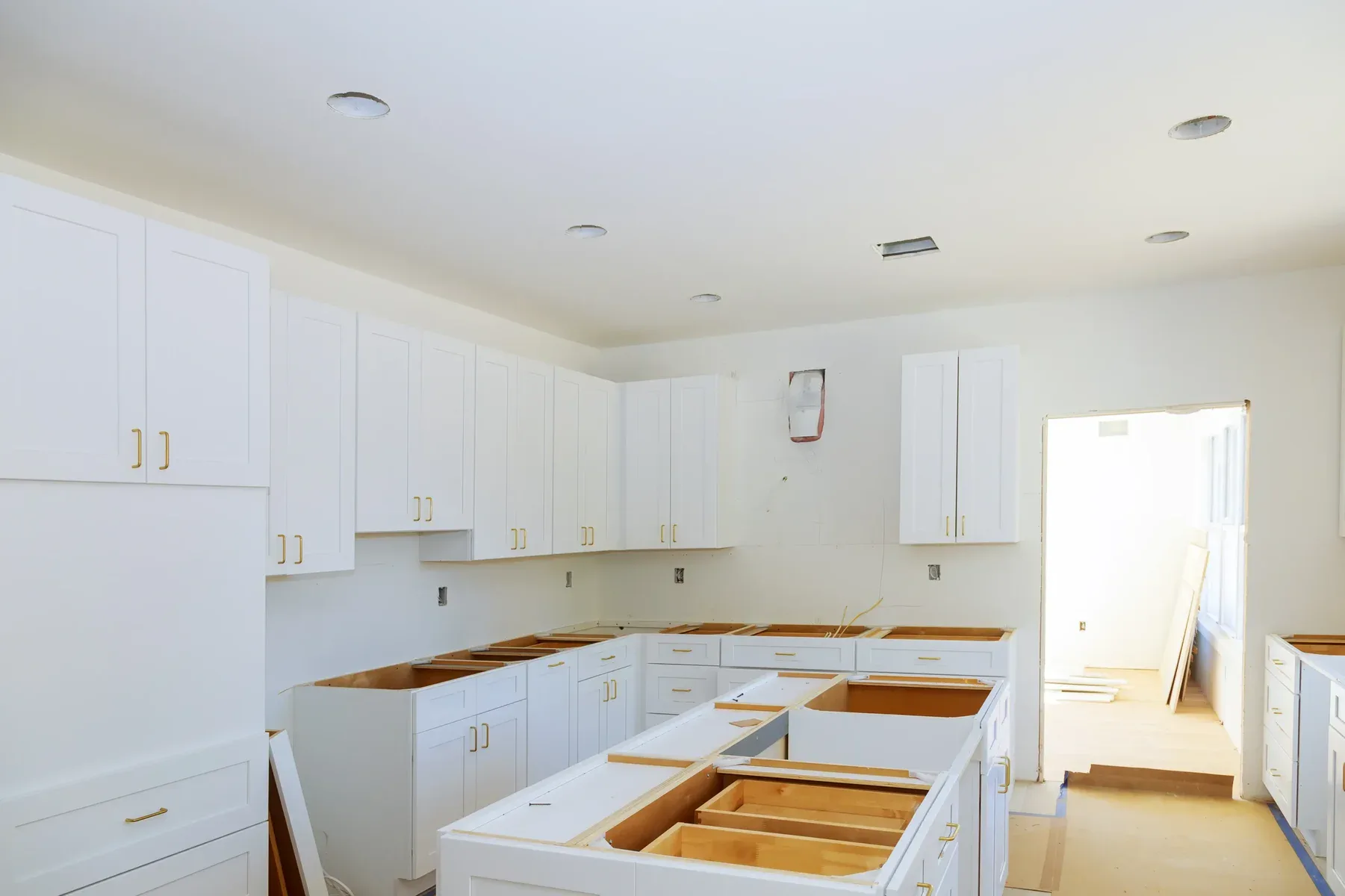 Unfinished kitchen with white cabinets and exposed wooden frames