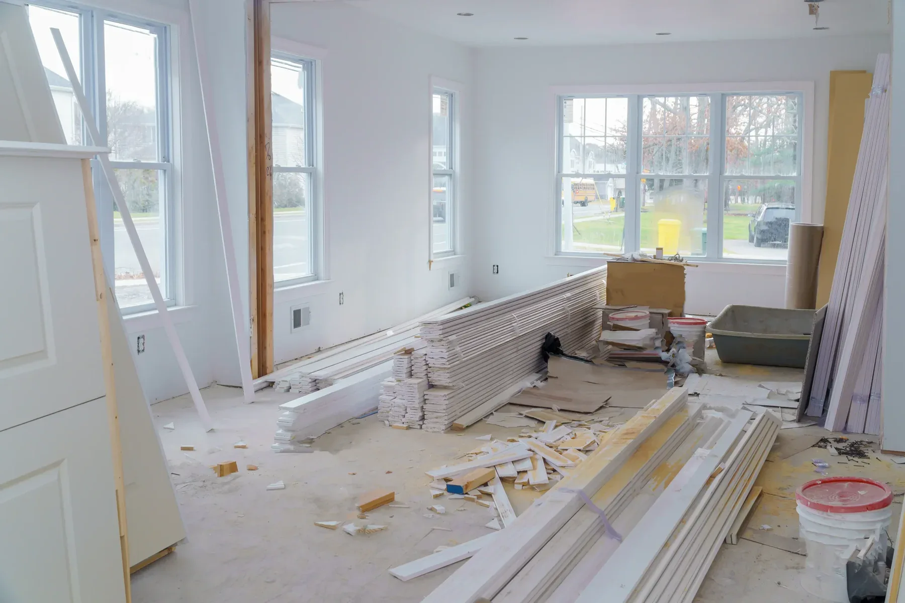 Interior of a room under construction with white walls and windows
