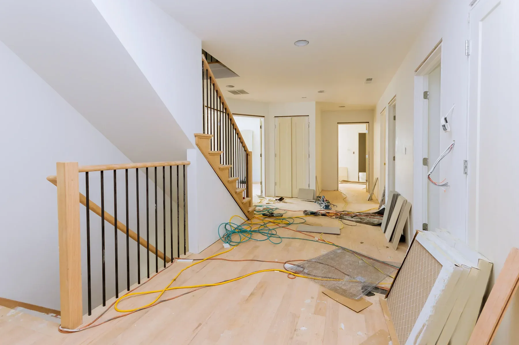 Interior hallway and staircase under construction with visible wires and tools