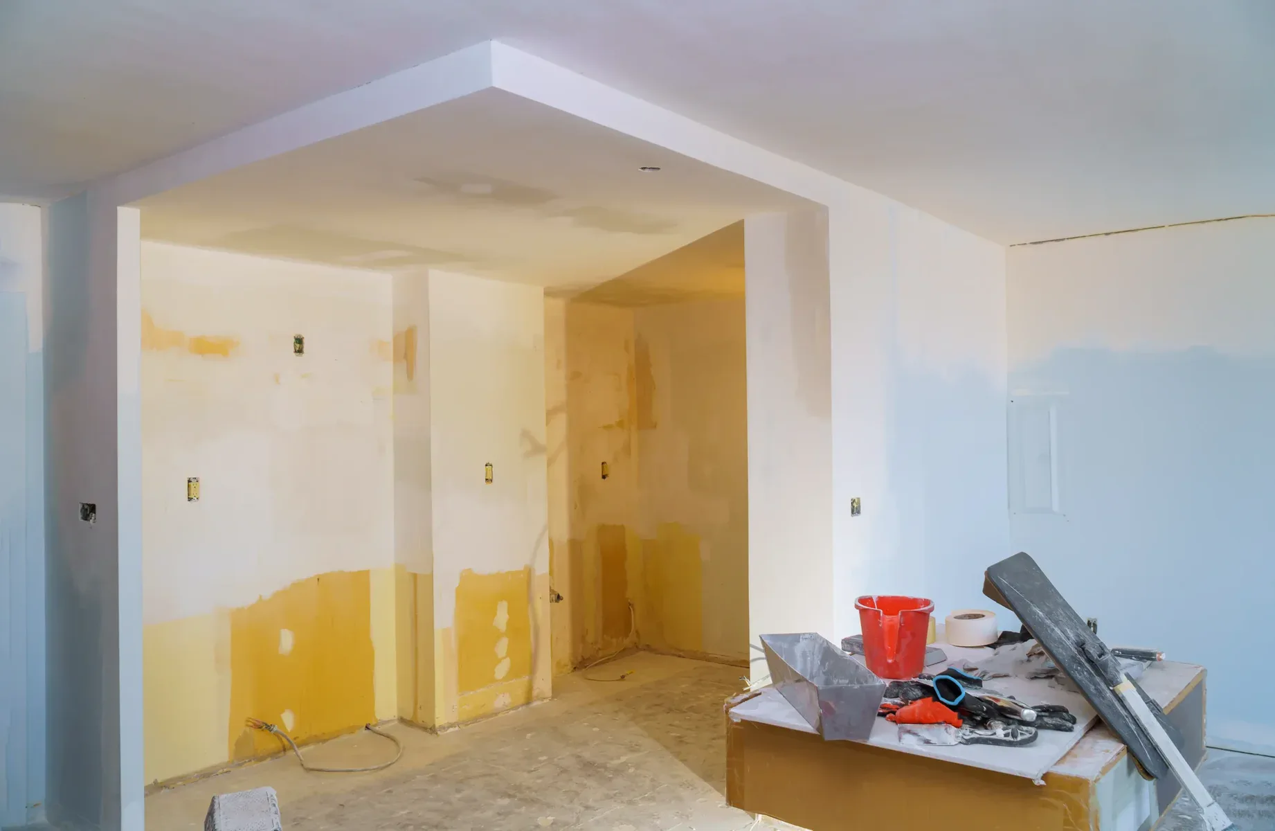 Room under construction with tools, partially painted walls, and drywall.