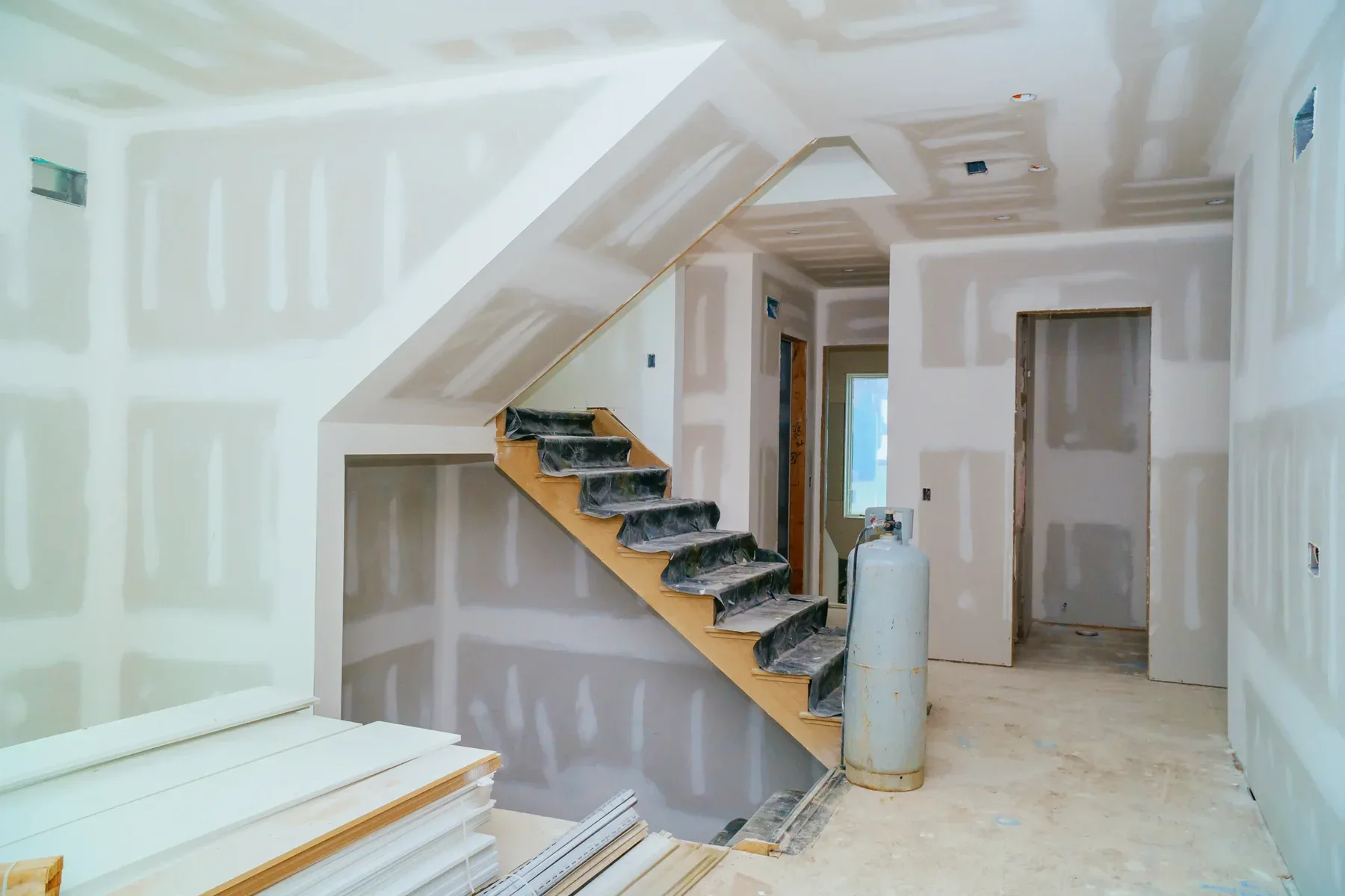 Interior of a house under construction with drywall installed and a staircase