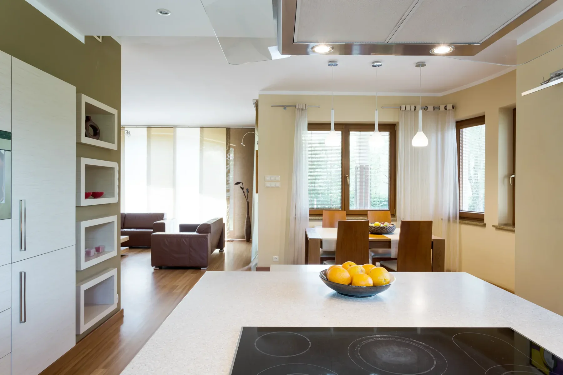 Modern open-plan kitchen and dining area with living room in background
