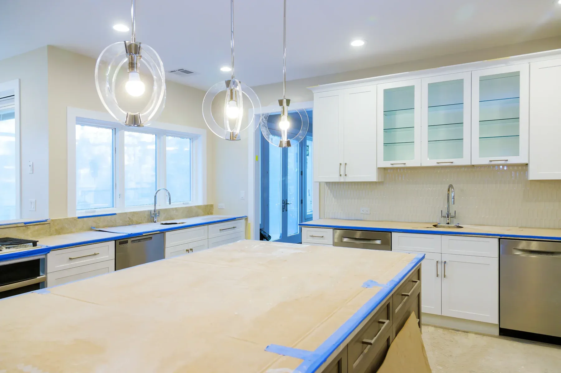 Unfinished kitchen with white cabinets, stainless steel appliances, and pendant lights