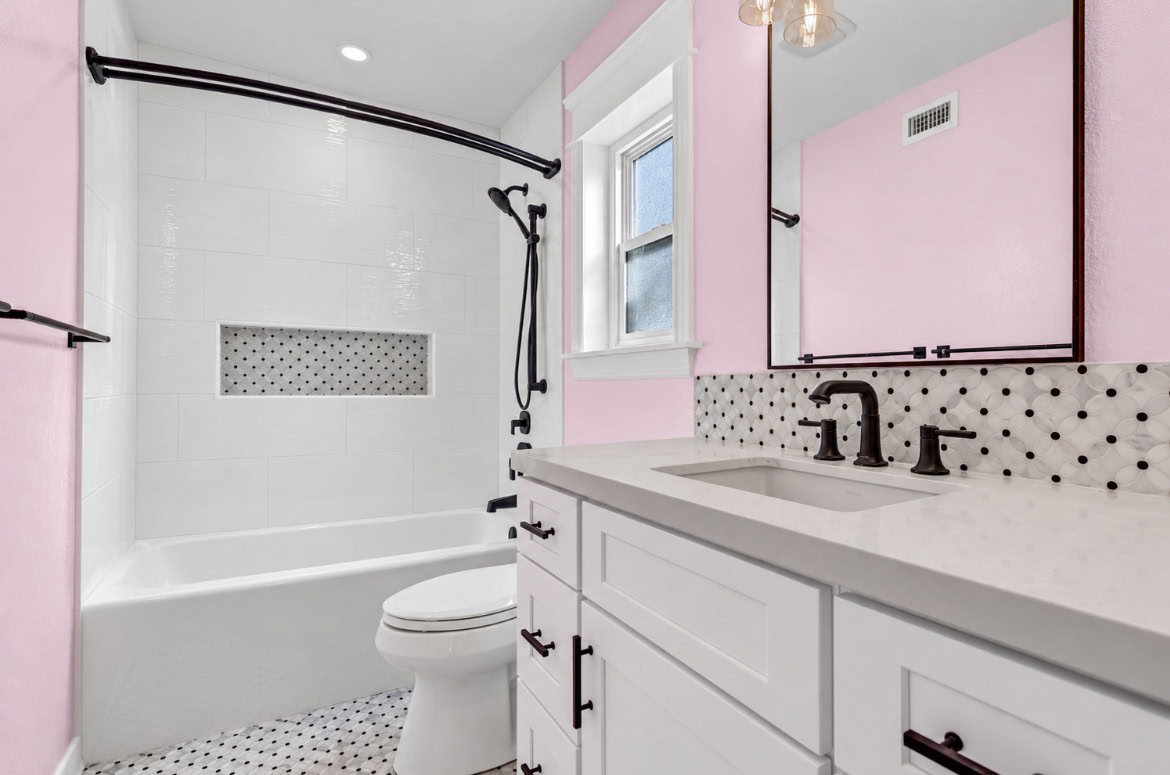 A modern pink and white bathroom featuring a bathtub and vanity.