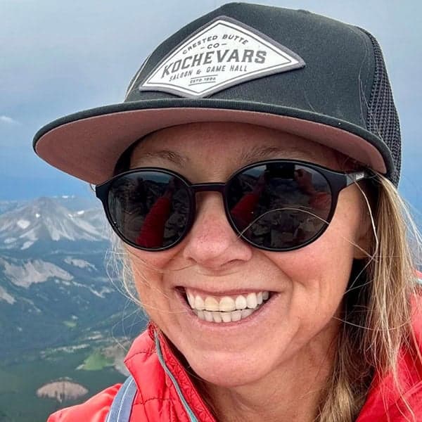 Theresa Henry smiles high atop a mountain wearing a Kochevars ball cap.