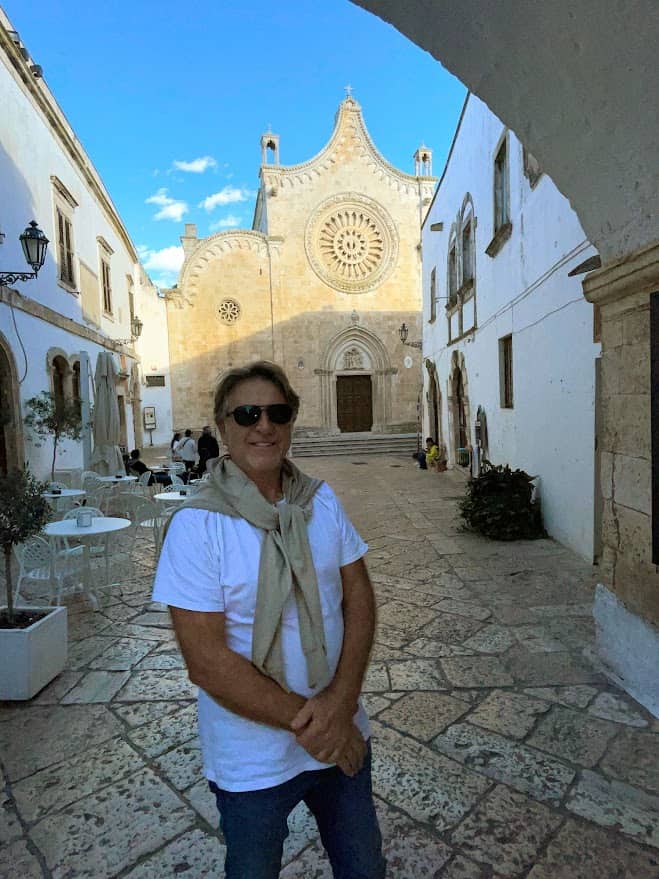 Herb Nagel of 'Herb Nagel Beyond, southern italy destinations expert, with Ostuni cathedral, one of the best southern italy destinations in background on a sunny day