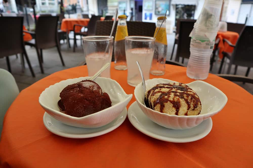 Pizzo's famous Tartufo nero (black) and bianco (white) ice cream in white dishes on an orange table tablecloth.