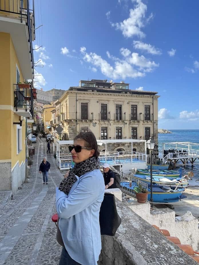 Woman in sunglasses enjoying seaside view in Scilla, Italy.