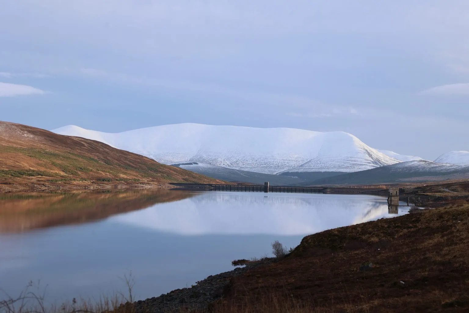 Snow covered Ben Wyvis it's reflection dominates the water in Glascarnoch Dam.