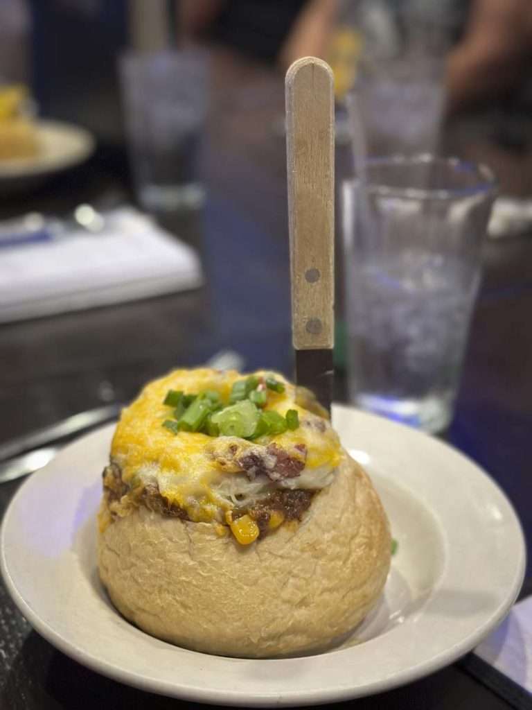 Yucca stuffed with meat and cheese, topped with green onions on a plate at a restaurant, close-up shot.