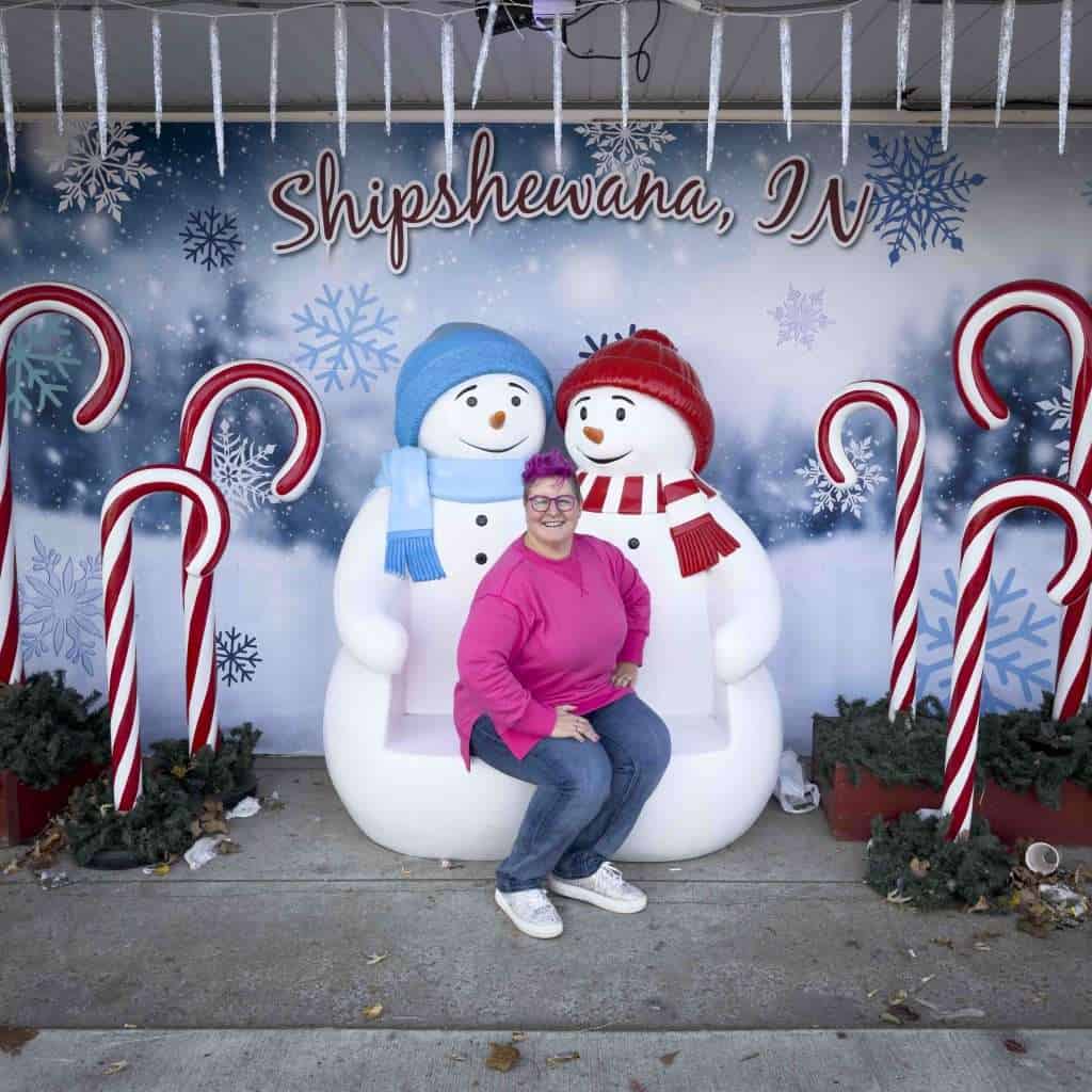 The pink-haired hip grandma poses on a snowman display.