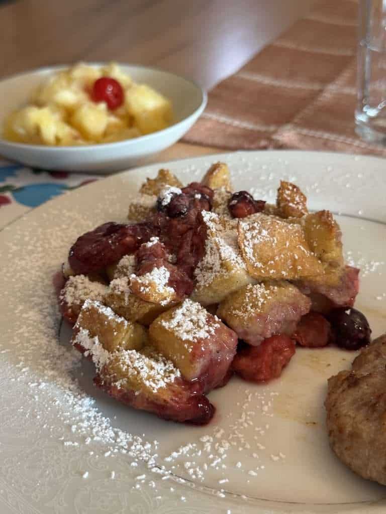 Homemade berry French toast casserole with sausage and fruit, served at a cozy Shipshewana bed and breakfast in LaGrange County, Indiana
