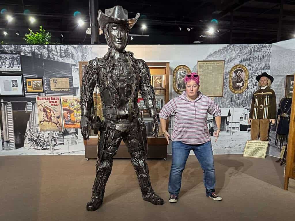 Hip Grandma posing with a cowboy statue made from metal parts at Historic Auto Attractions in Roscoe, Illinois.