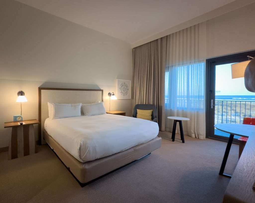 Guest room with a king bed and private balcony overlooking the Gulf at The Lodge at Gulf State Park in Gulf Shores, Alabama.