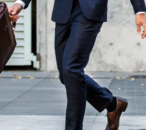 Businessman walking in formal suit on city sidewalk, carrying a briefcase.