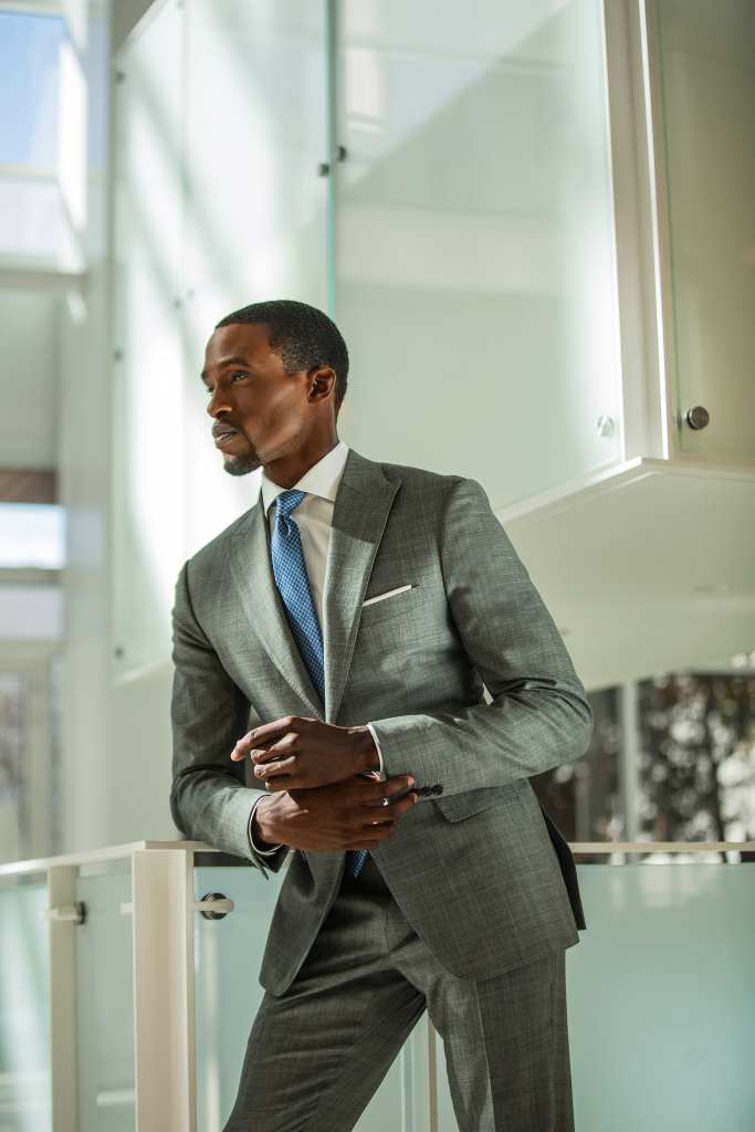 Business professional in tailored gray suit looking thoughtfully outside.