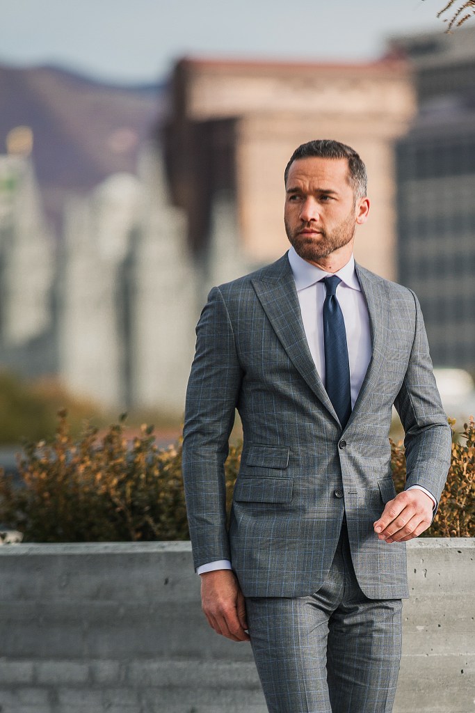 Professional man in a gray suit standing outside in an urban setting.