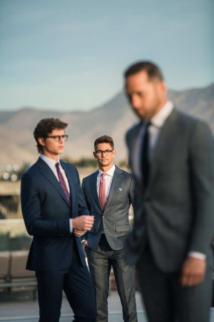 Group of business professionals discussing pricing options outdoors with mountains in background.
