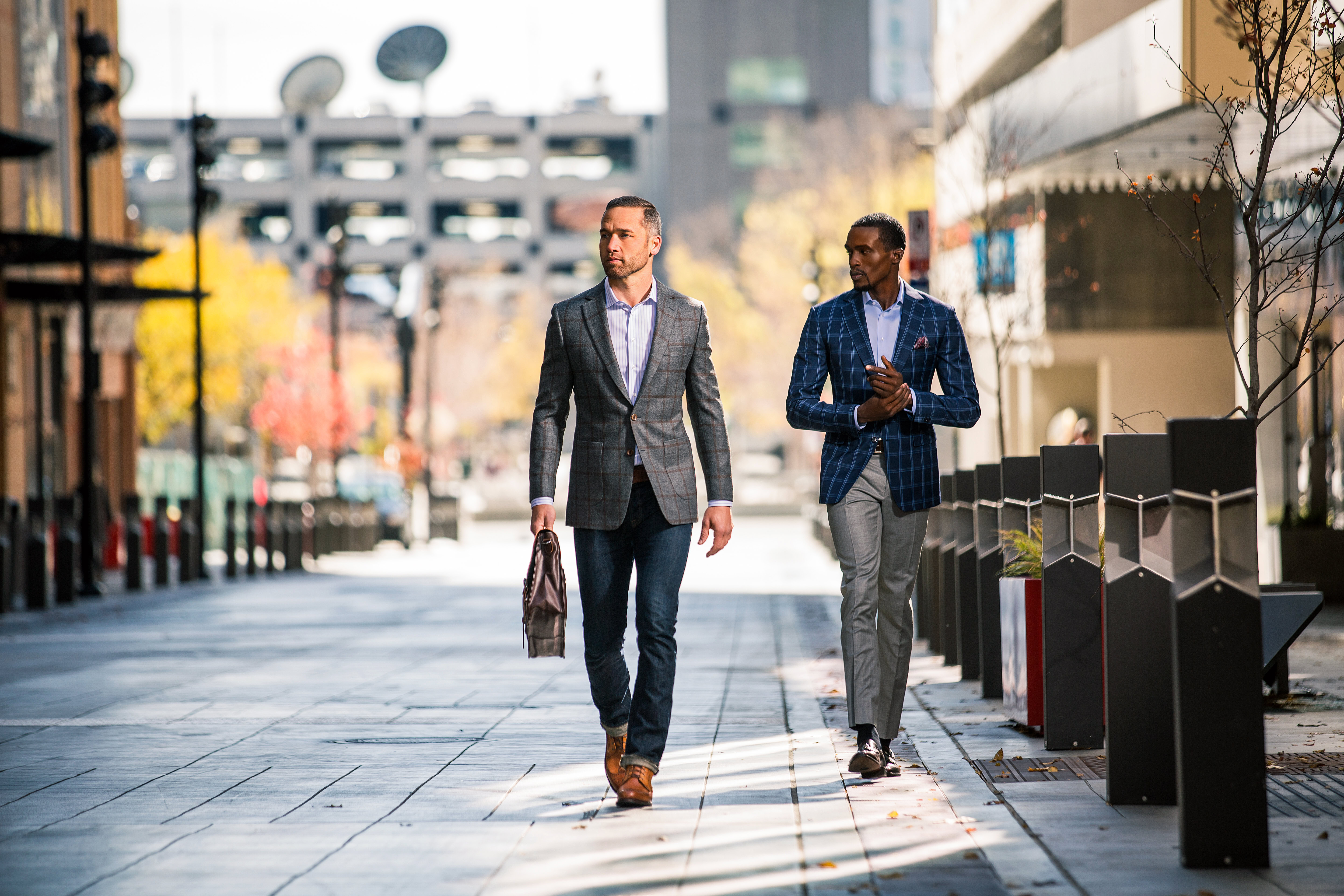 Business professionals walking outdoors in a city street, dressed in formal suits.