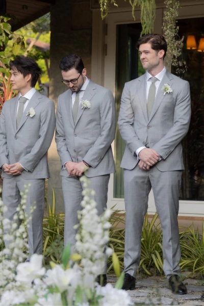 Groom and groomsmen dressed in stylish gray suits during outdoor wedding ceremony, showcasing formal.