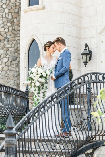 Wedding couple embracing on castle staircase with romantic atmosphere.