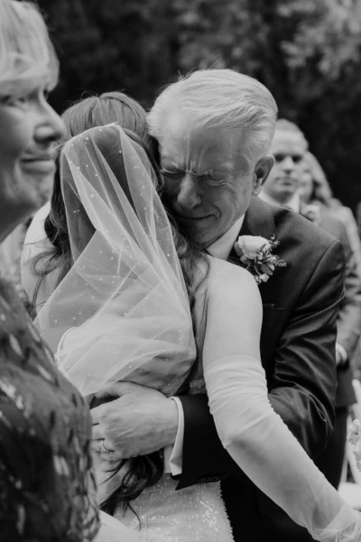 Emotional moment of a bride and her father sharing a heartfelt hug at a wedding.