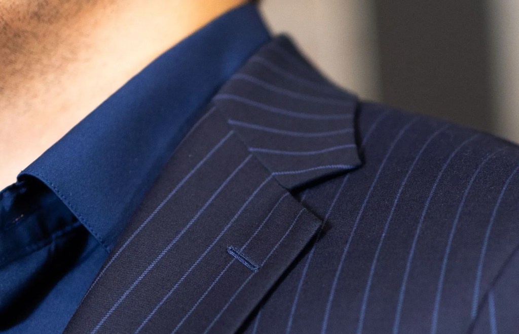 Close-up of navy pinstripe suit jacket and blue shirt.