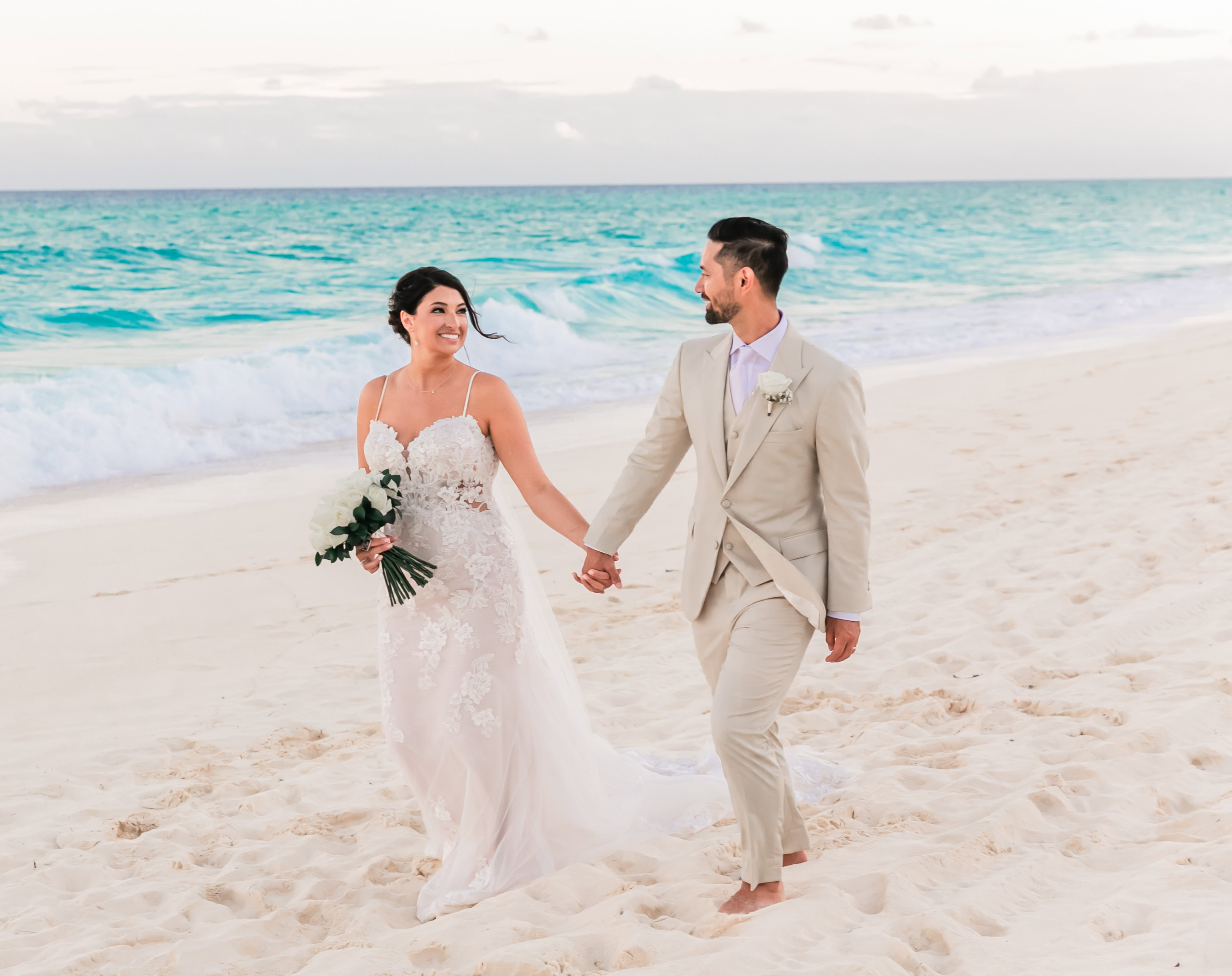 Bride and groom walking on the beach after wedding ceremony.