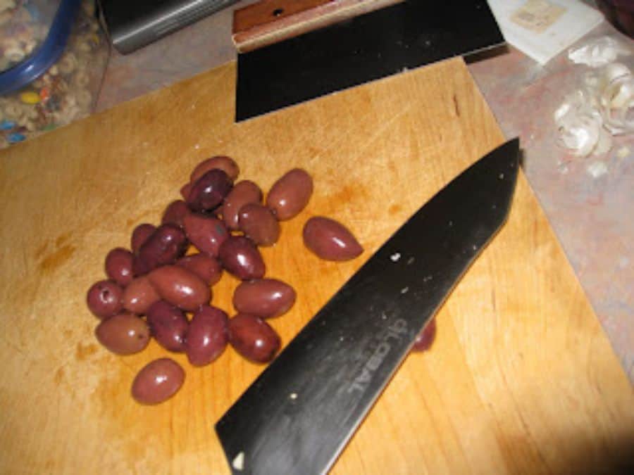 Image shows knife laying flat on kalamata olives.