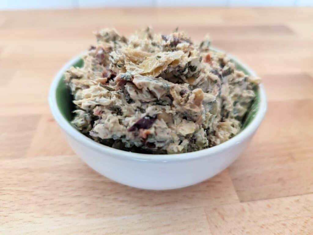 Image shows Tuscan artichoke and sundried tomato dip in a bowl.