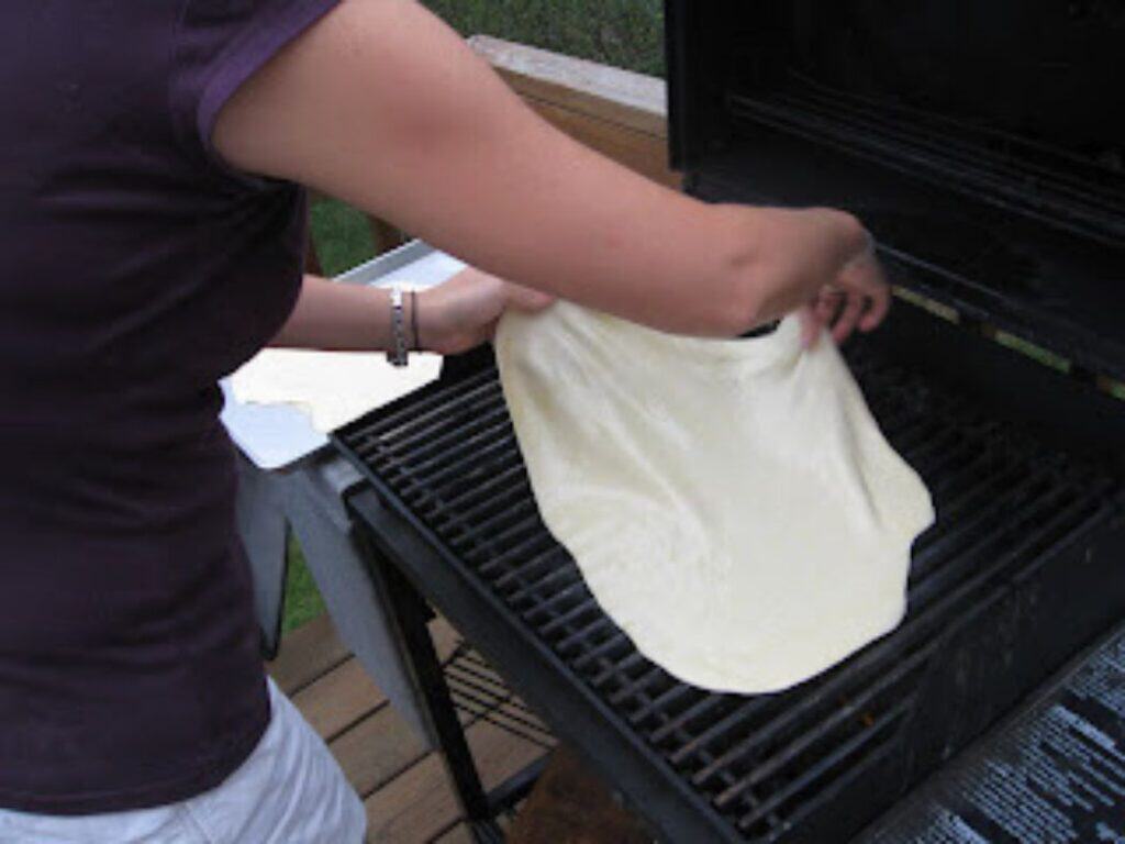 Image shows flattened dough on the grill.