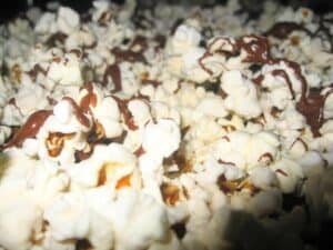 Image shows popcorn drizzeled with chocolate.
