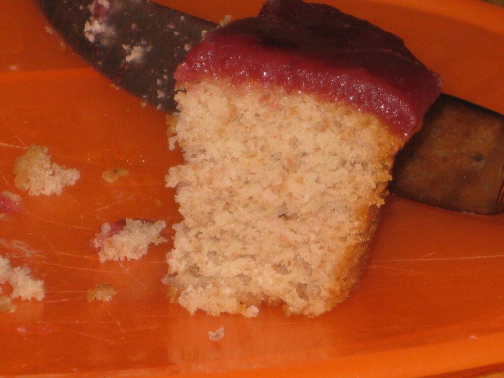 Image shows half-eaten strawberry cupacke with cherry glaze.