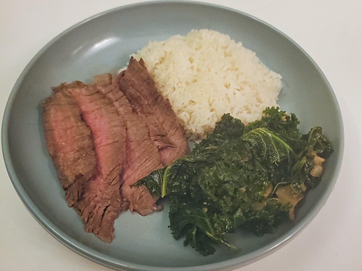 Overhead of a plate of sliced steak rice and garlic sesame kale.