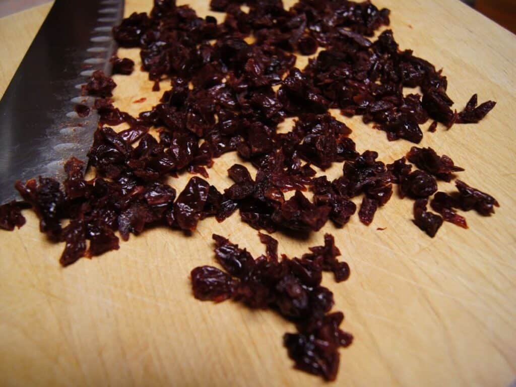 Image shows chopped cherries on a chopping board.