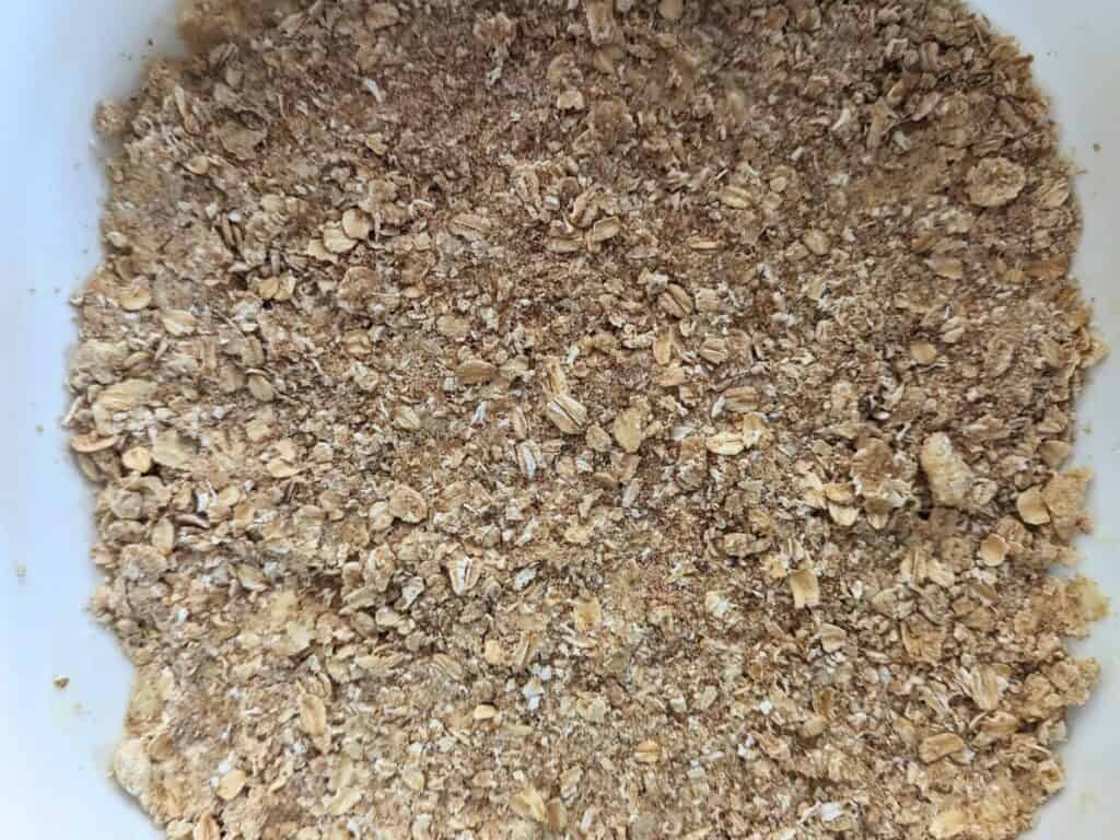 Image shows an overhead of Jam bar crust pressed into a pan.